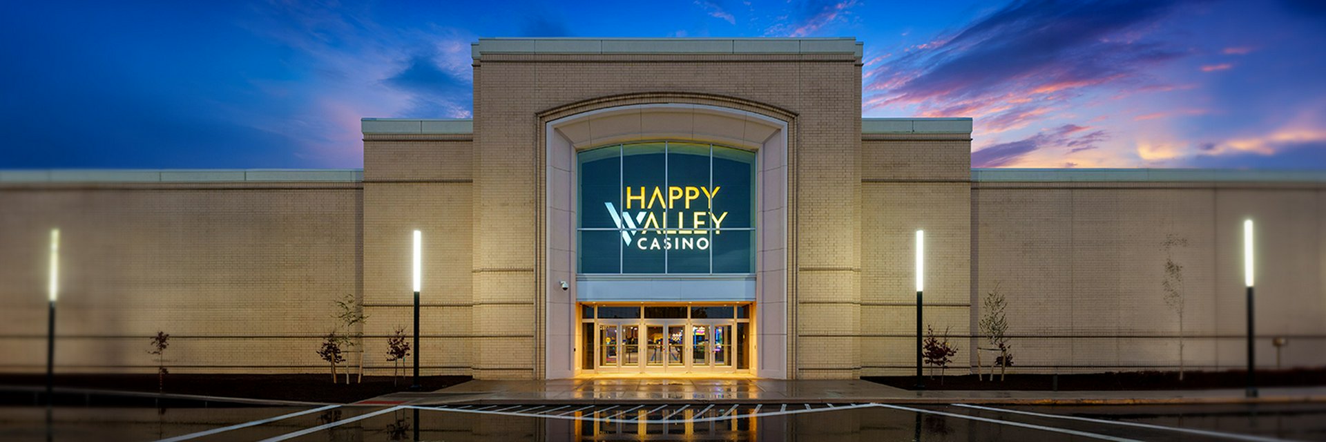 Guests walking toward the illuminated entrance of Happy Valley Casino at dusk in State College, Pennsylvania.