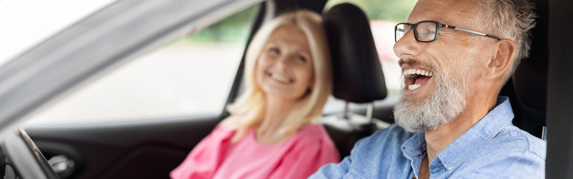 Older couple smiling and talking inside a car while driving to Happy Valley Casino in State College, Pennsylvania.